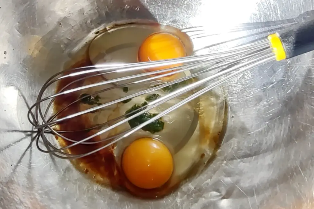 Making a Thai omelette in a stainless steel bowl using a baloon whisk